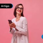 Imagem mostra jovem sorrindo segurando celular.
