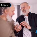 Duas pessoas de mais idade sorrindo olhando para o celular