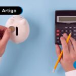 Pessoa colocando moeda em cofrinho e calculadora ao lado.