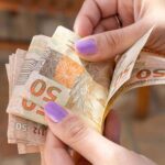 Mãos com notas de 50 reais na mão