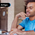 imagem de jovem vestindo camisa azul repousando a mão no queixo e olhando para a tela do notebook