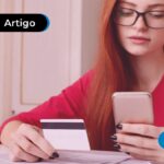Jovem com expressão preocupada segurando celular e cartão de crédito branco.