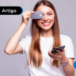 imagem de mulher com camisa branca segurando um cartão de crédito e celular