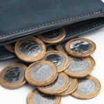 a imagem mostra uma carteira com várias moedas de R$1,00, simbolizando o saque extraordinário.