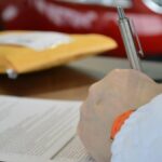 imagem mostra uma pessoa assinando um contrato.
