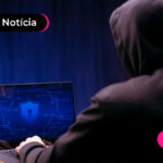 uma pessoa com capuz em frente a um notebook.