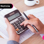 mãos segurando calculadora apoiada em uma mesa