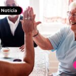 imagem de três idosos sorrindo sentados em volta de mesa