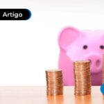 Três pilhas de moedas em cima de uma mesa com um cofre de porco atrás