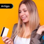 Mulher sorrindo com sacola de compras e cartão de credito