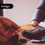 imagem de mão segurando cartão de crédito dourado aproximando de máquina