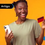 Mulher sorrindo com celular e cartão de credito em mãos