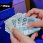 Pessoa segurando varias notas de cem reais