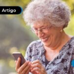 Senhora de cabelos brancos segurando um celular e sorrindo