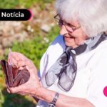 mulher no jardim colocando dinheiro na carteira