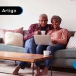Casal de idosos sentados no sofá com computador nas pernas