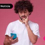 Imagem de homem jovem olhando para o celular pensando