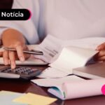 Pessoa usando uma calculadora sob uma mesa