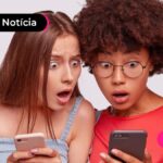 Duas pessoas olhando com cara de espanto para um celular