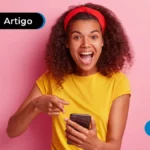 Imagem mostra jovem feliz apontando para o celular.
