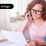 Pessoa segurando o papel com uma mão e um celular com a outra