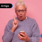 Pessoa de cabelos brancos e sueter segurando um celular