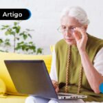 Pessoa de idade sentada a frente de um computador