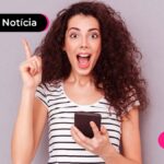Pessoa de cabelos cacheados e blusa listrada segurando um celular