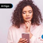 Pessoa de cabelos cacheados segurando um celular