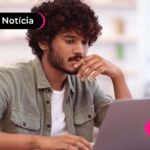 Jovem vestindo roupas sociais e lendo algo no notebook com expressão de concentrado.