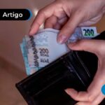 Pessoa colocando dinheiro em uma carteira preta.