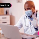 Medico de mascara a frente de um computador
