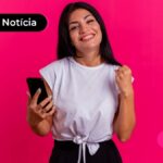 Jovem sorridente segurando um celular.