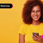 imagem de pessoa de amarelo olhando para o celular e sorrindo