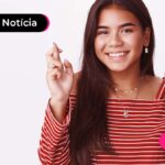 Jovem sorrindo com os dedos cruzados.