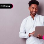 Imagem mostra jovem sorridente lendo algo em um computador.