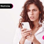 Imagem mostra jovem lendo algo no celular.