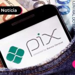 Imagem mostra celular em bolso de roupa jeans com notas de cinquenta e cem reais.