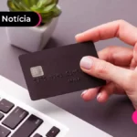 Pessoa segurando um cartão de sobre um notebook