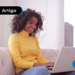 Imagem jovem sorridente lendo algo no computador.