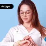 Imagem mostra jovem olhando para relógio de pulso.