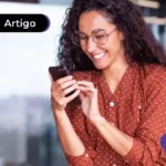 Imagem de jovem sorrindo olhando para o celular.