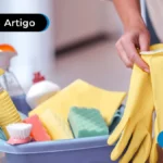 Imagem de pessoa colocando luva e produtos de limpeza ao lado.