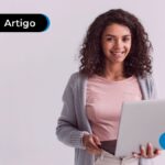 Imagem mostra jovem feliz segurando um notebook.