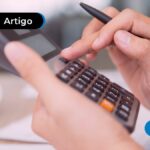 Mão de pessoa usando calculadora e segurando caneta preta.