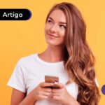 Imagem mostra jovem feliz segurando celular.