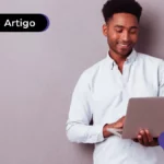 Jovem sorrindo mexendo em computador.