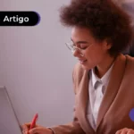 Jovem usando óculos de leitura mexendo no computador.