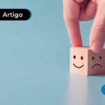 Dado de madeira com desenho de carinha feliz e triste em cada lado.