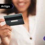 Pessoa sorrindo segurando cartão de crédito.